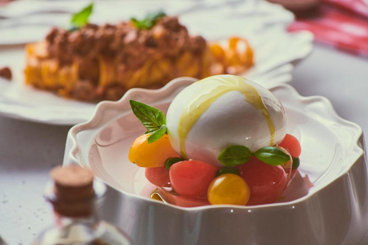 Five Jumeirah Village 두바이 외부 사진 The photo showcases a beautifully presented dish featuring a large ball of fresh mozzarella cheese, sitting atop a colorful assortment of small tomatoes. The tomatoes are a mix of red and yellow, creating a vibrant visual contrast. Fresh basil leaves