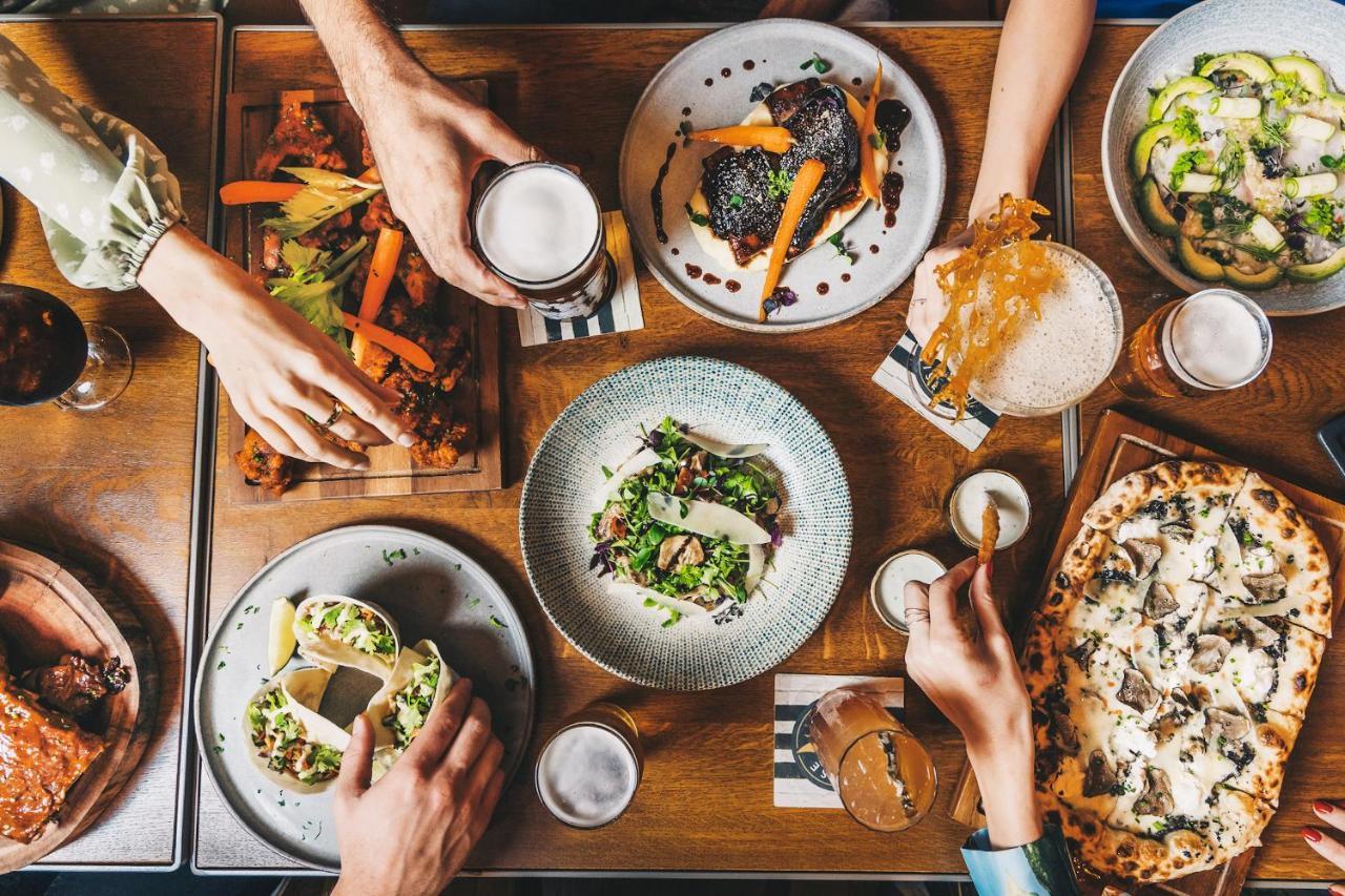 Five Jumeirah Village 두바이 외부 사진 The photo displays a table filled with a variety of delicious food and drinks. There are several dishes, including a colorful salad in a round bowl, tacos, and what appears to be a pizza. On the side, there are also wooden platters with grilled veget